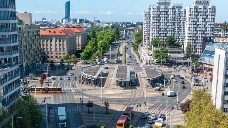 Wide view of city intersection and public transportation hub surrounded by modern and historic buildings, depicting urban mobility and architecture